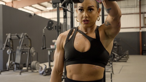 Figure competitor training shoulders in the gym