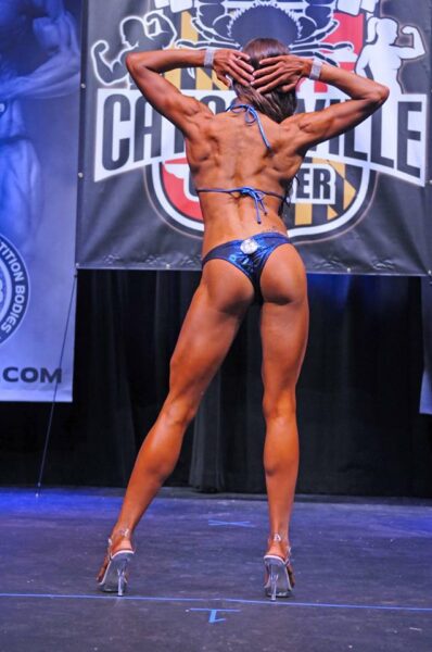 Bikini competitor on stage showing back development